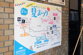 煉瓦風にタイルが貼られた壁に、「ミュージアムで夏まつり」の会場案内が掲示されている。
