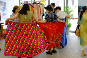 華やかなプリント柄の布を腰に巻こうとする女性達。
