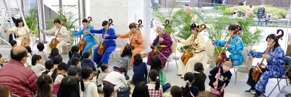 弦楽器を構えた女性9人が並ぶ。