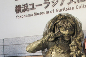 花嫁の銅像のようなメイクをした女性が両手でピースサイン。